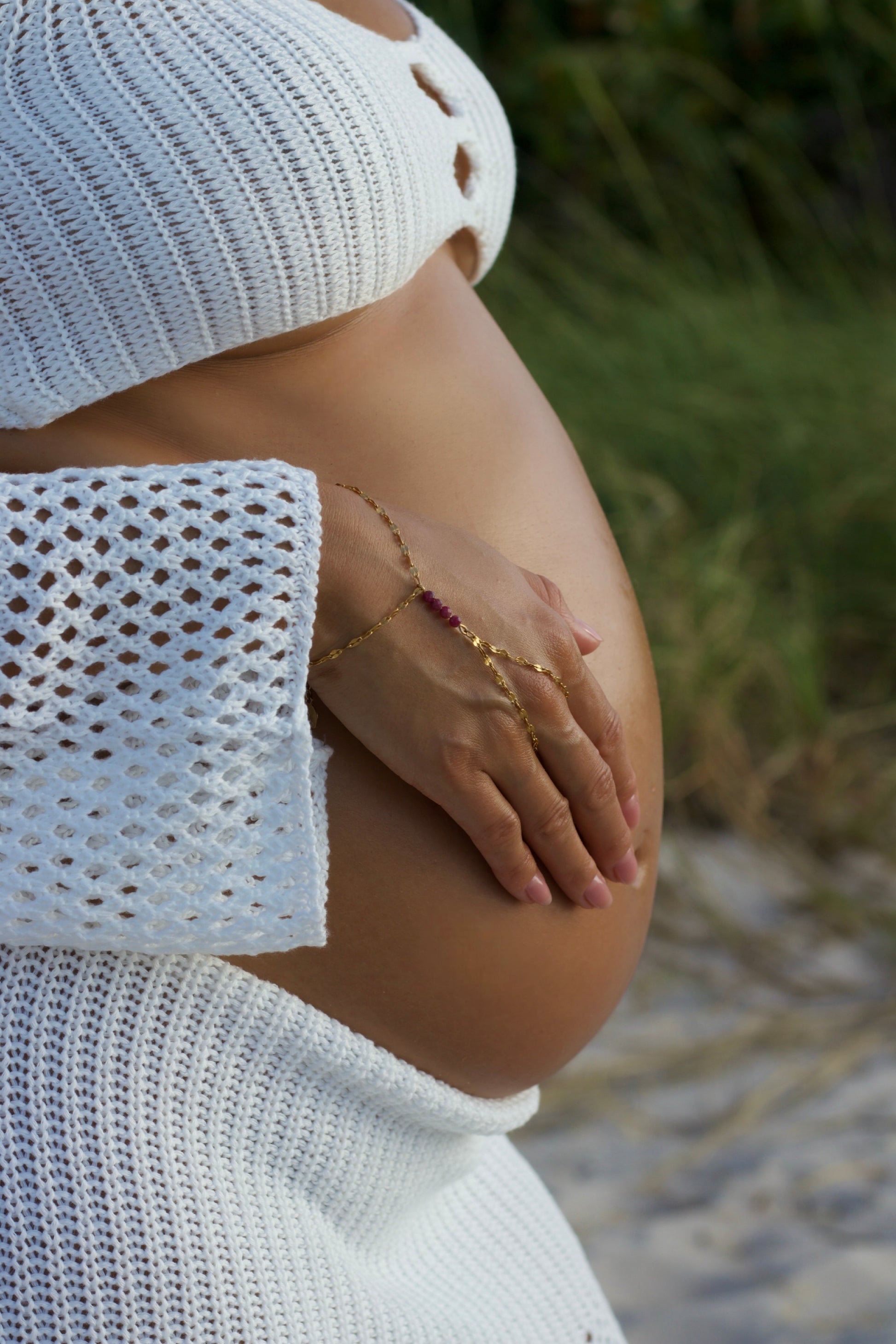 Pregnant belly with genuine ruby hand chain bracelet with blurred natural background