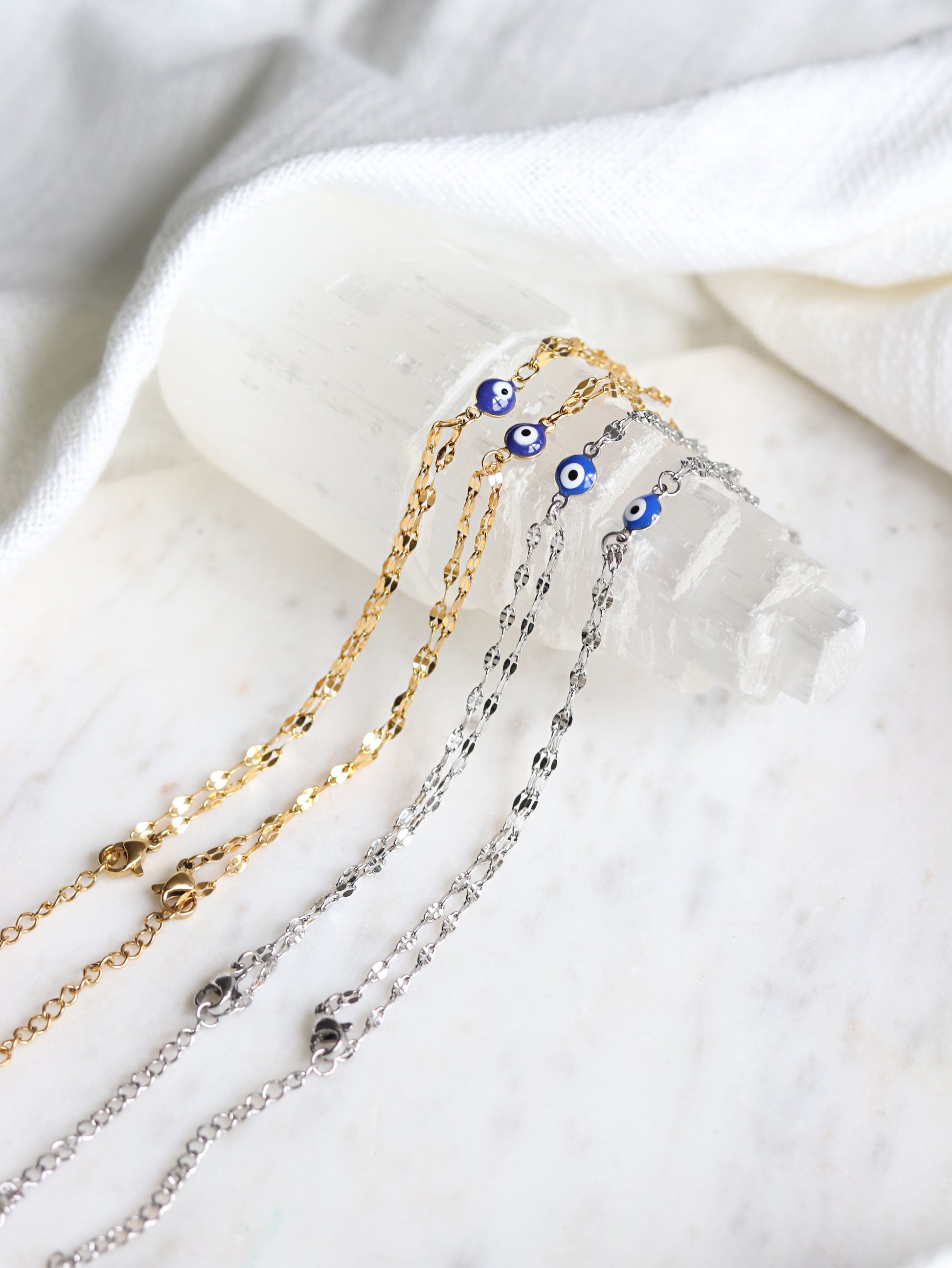 four hand chain bracelets with evil eye pendants on a selenite crystal tower