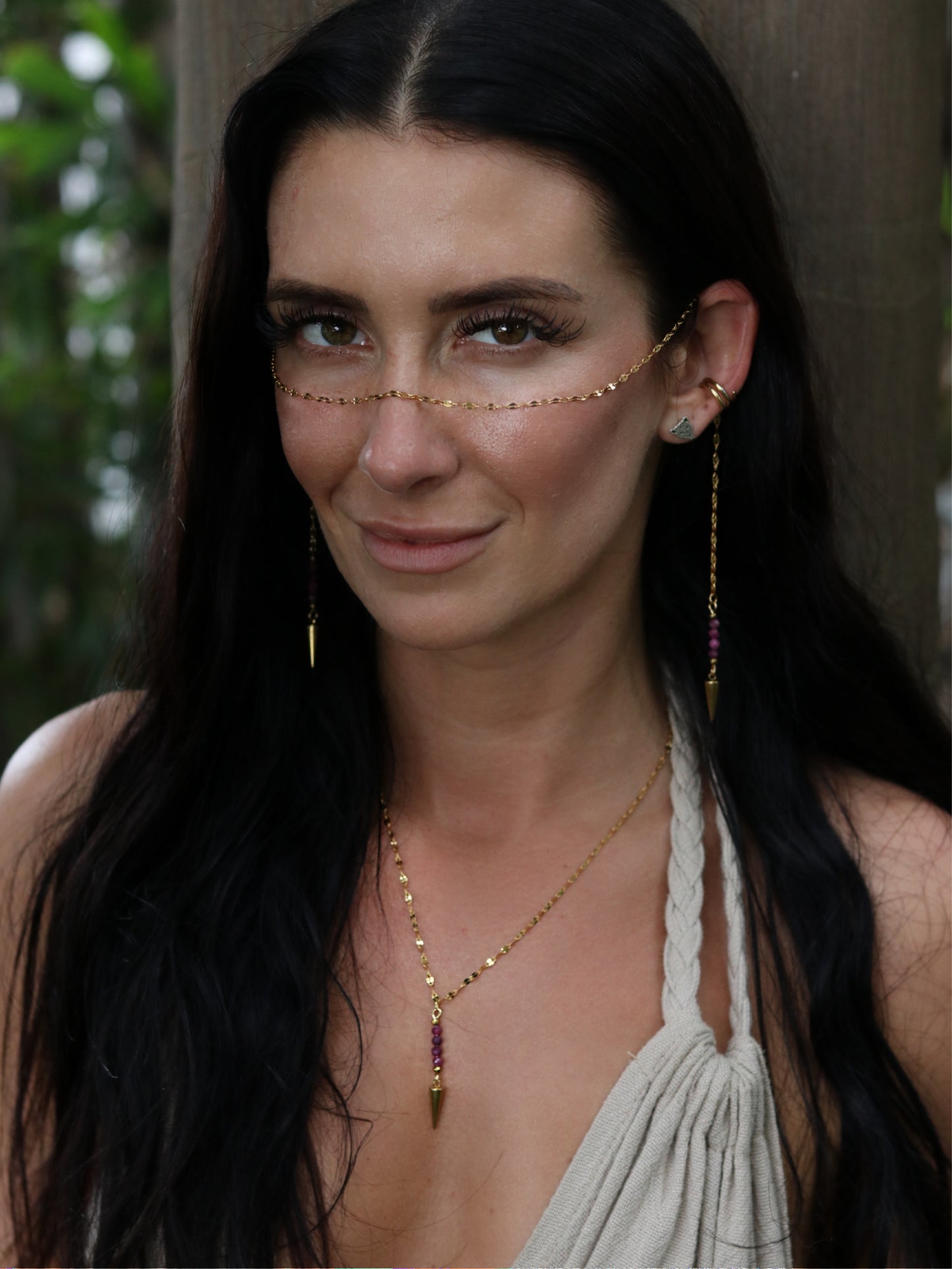 Woman wearing gold jewelry with a blurred natural background
