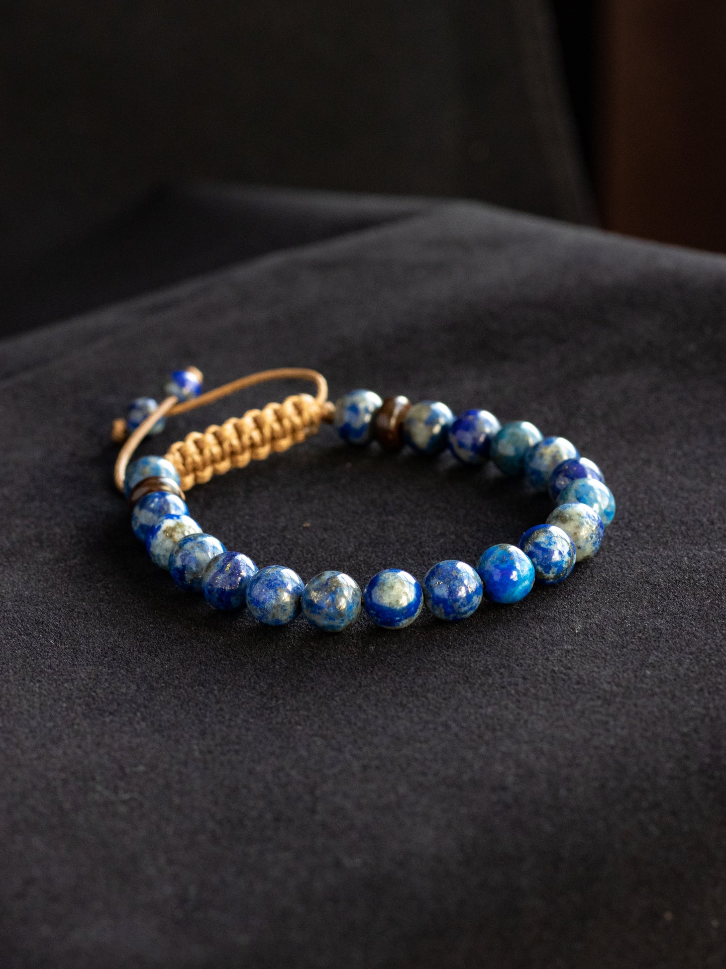 Lapis Lazuli beaded bracelet with a light brown cord on a dark background