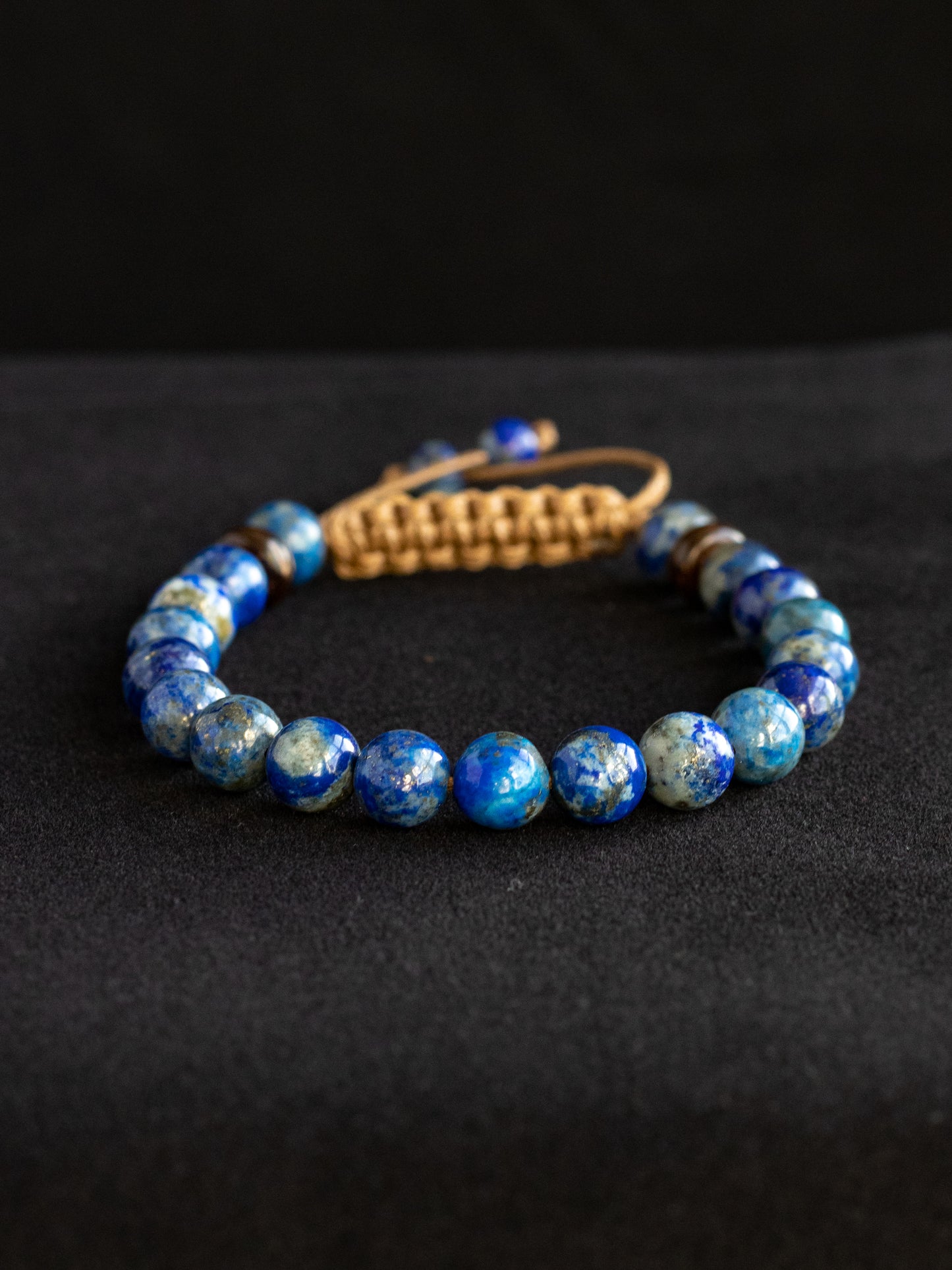 Lapis Lazuli beaded bracelet with a brown clasp on a black background