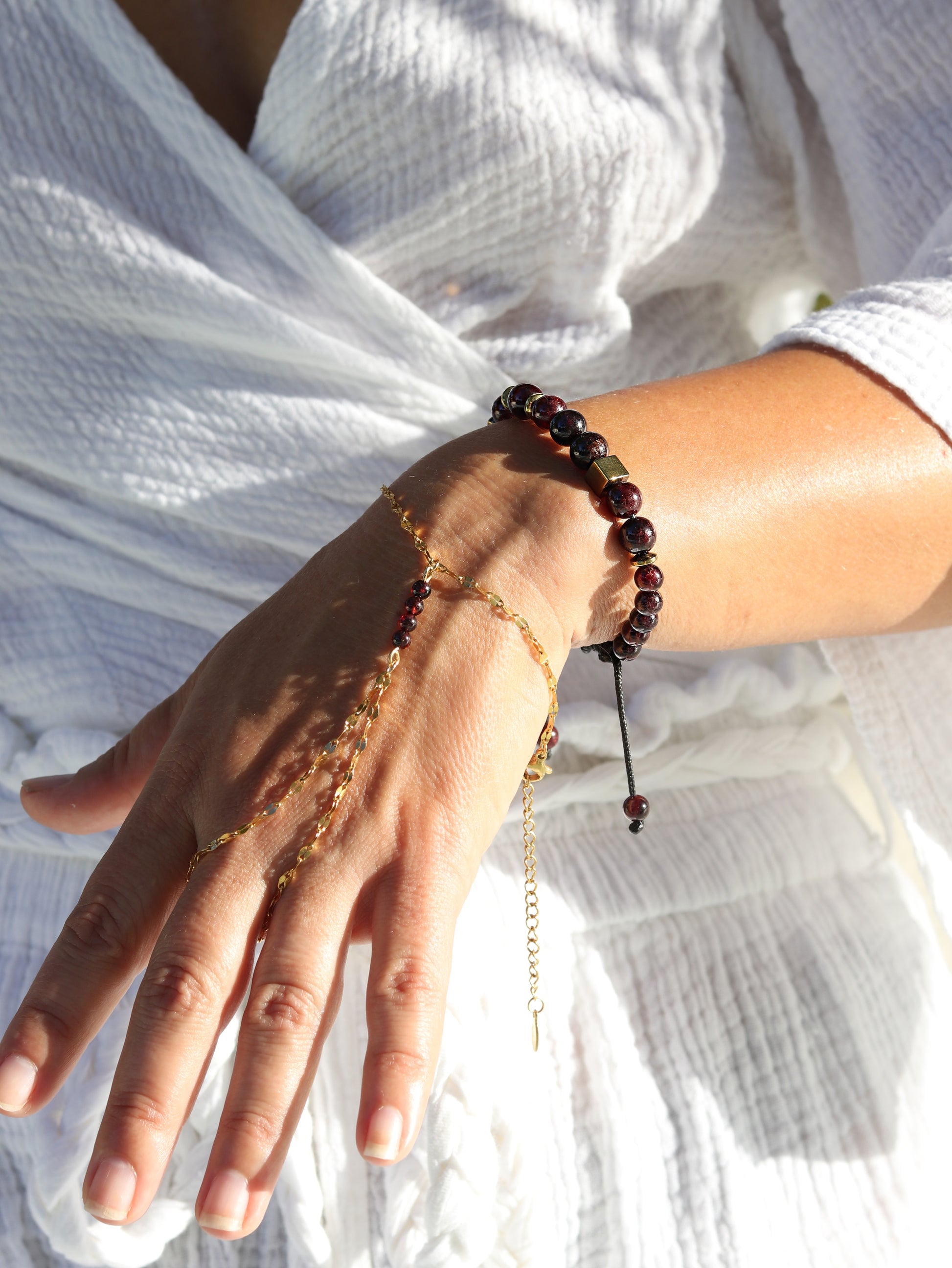 Red garnet hand chain bracelet with gold chain connecting wrist to finger divine feminine jewelry