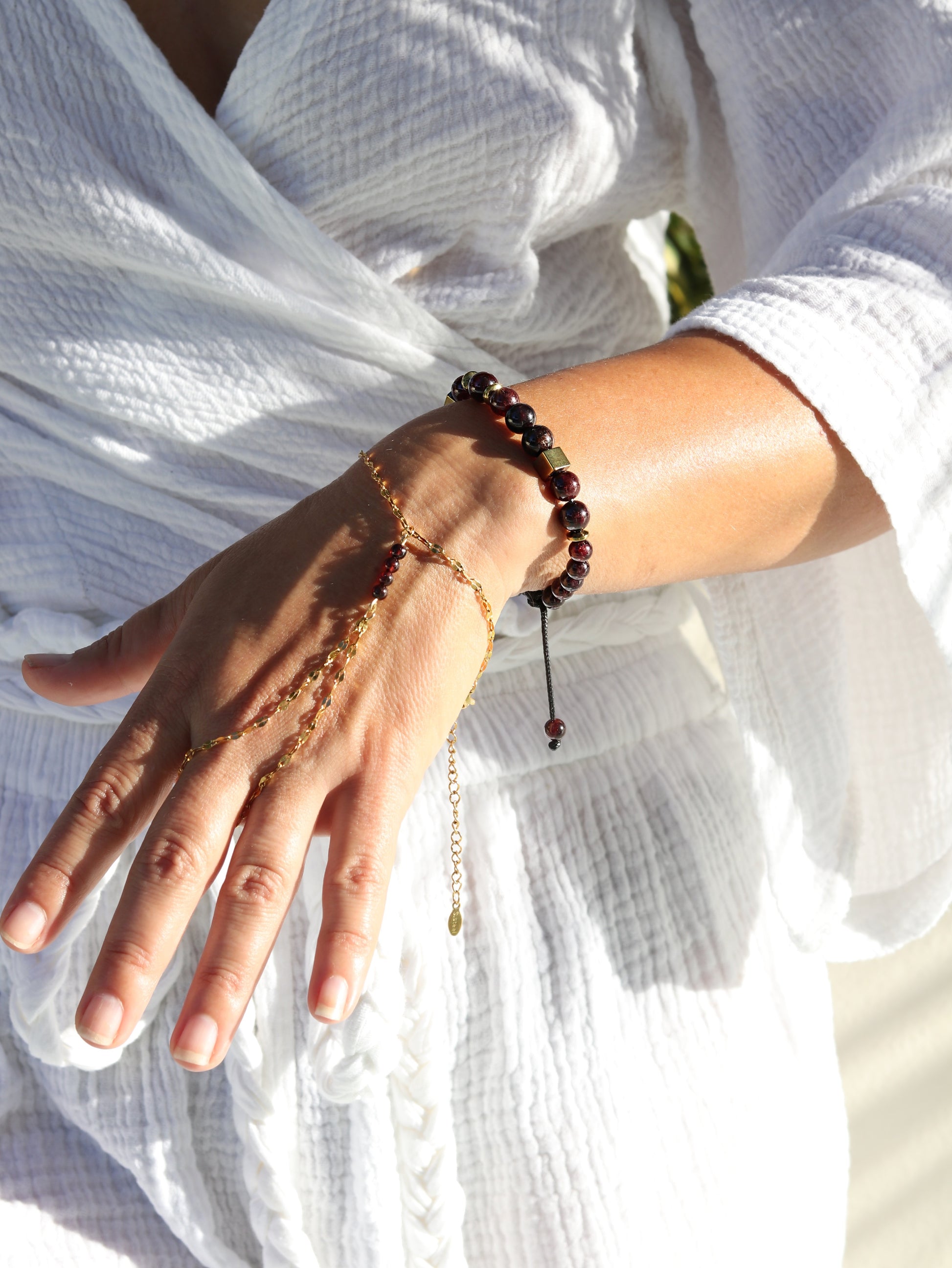 Woman wearing red garnet hand chain bracelet showing passionate gemstone beads and gold connecting chain