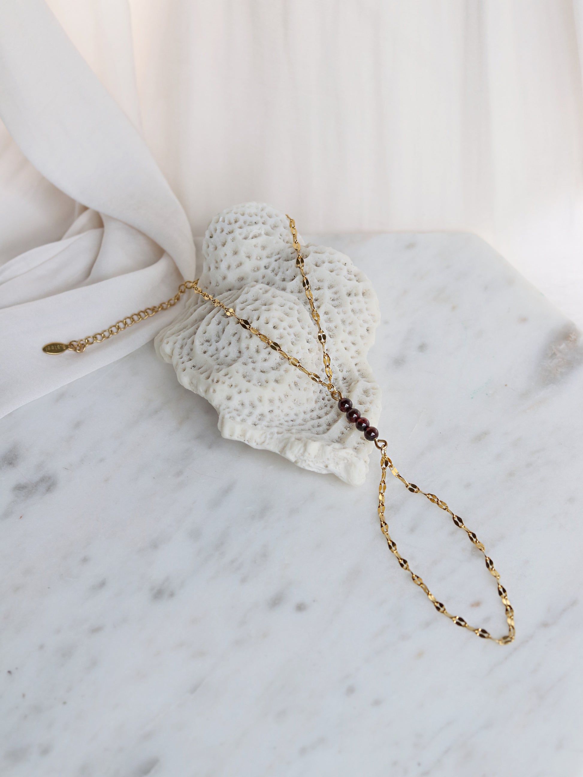 Close up red garnet hand chain bracelet with adjustable gold chain spiritual passion jewelry