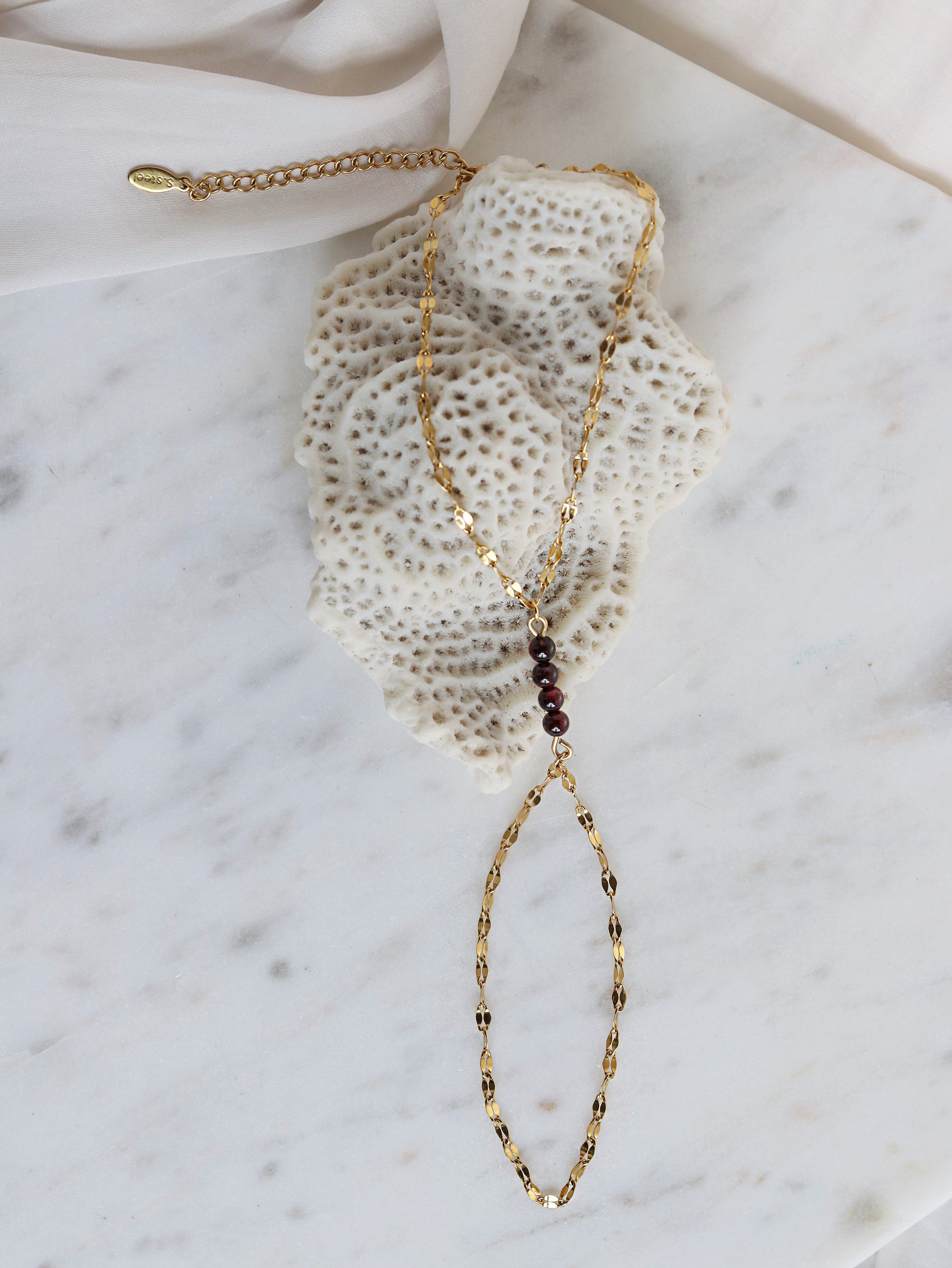 Close up red garnet hand chain bracelet with adjustable gold chain spiritual passion jewelry