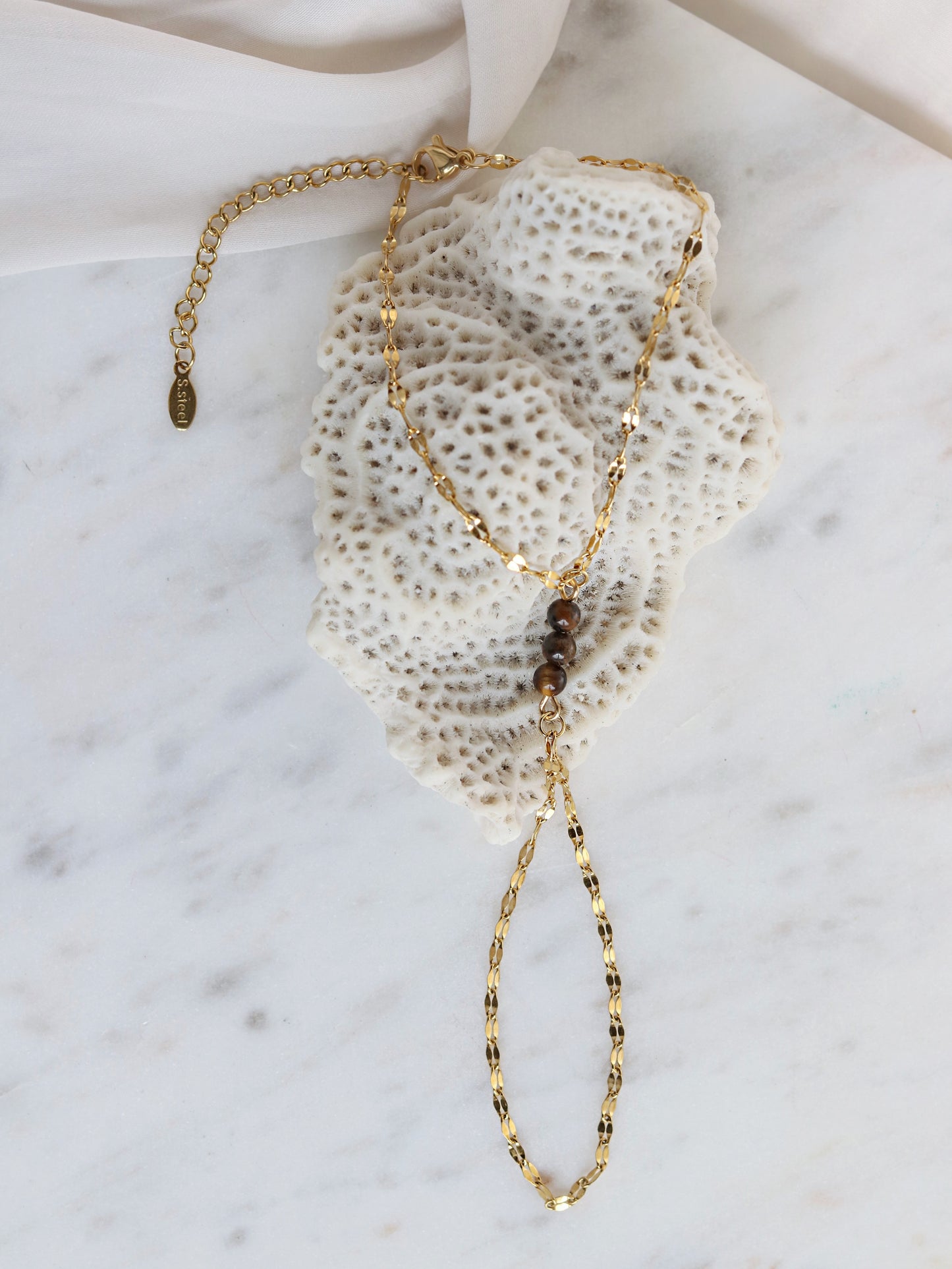 Gold chain bracelet on a textured white surface