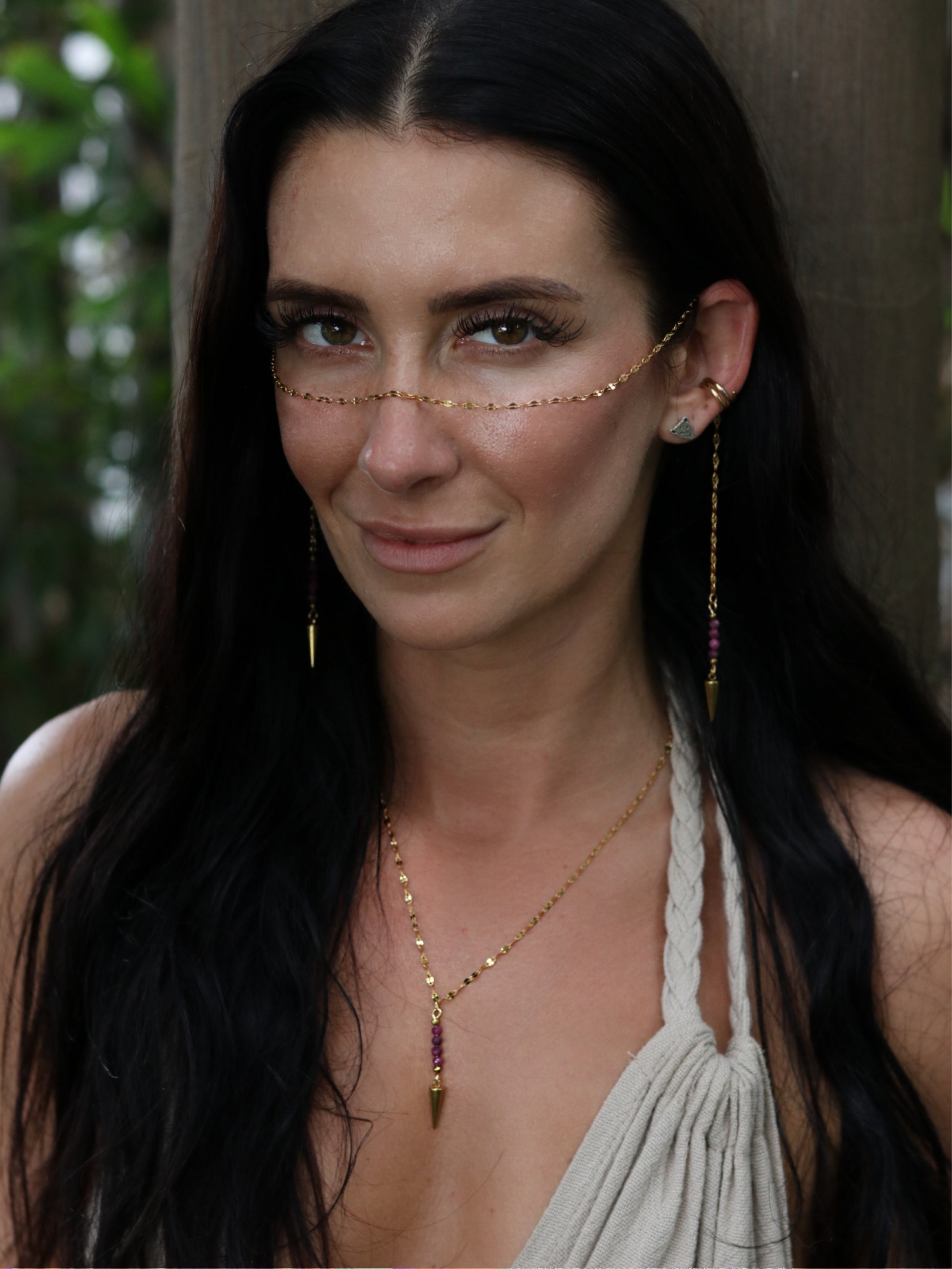 Woman wearing gold jewelry with a blurred natural background