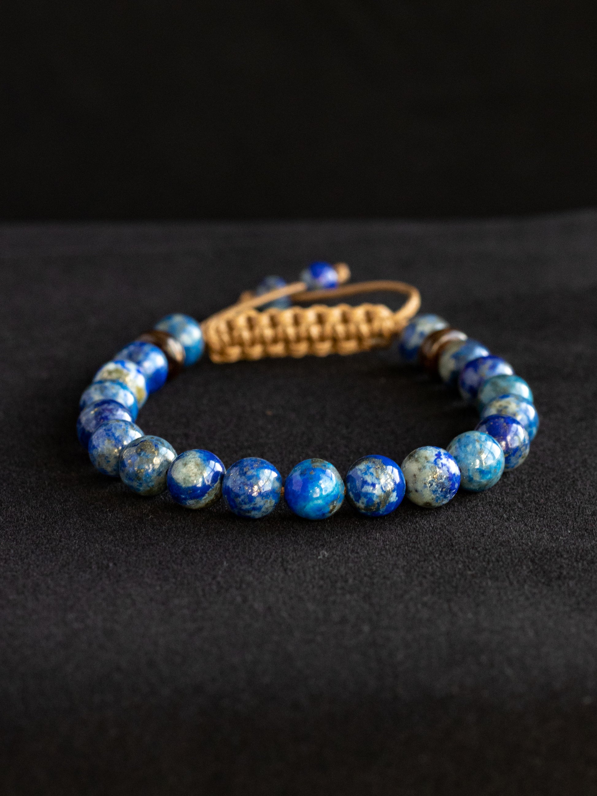 Lapis Lazuli beaded bracelet with a brown clasp on a black background