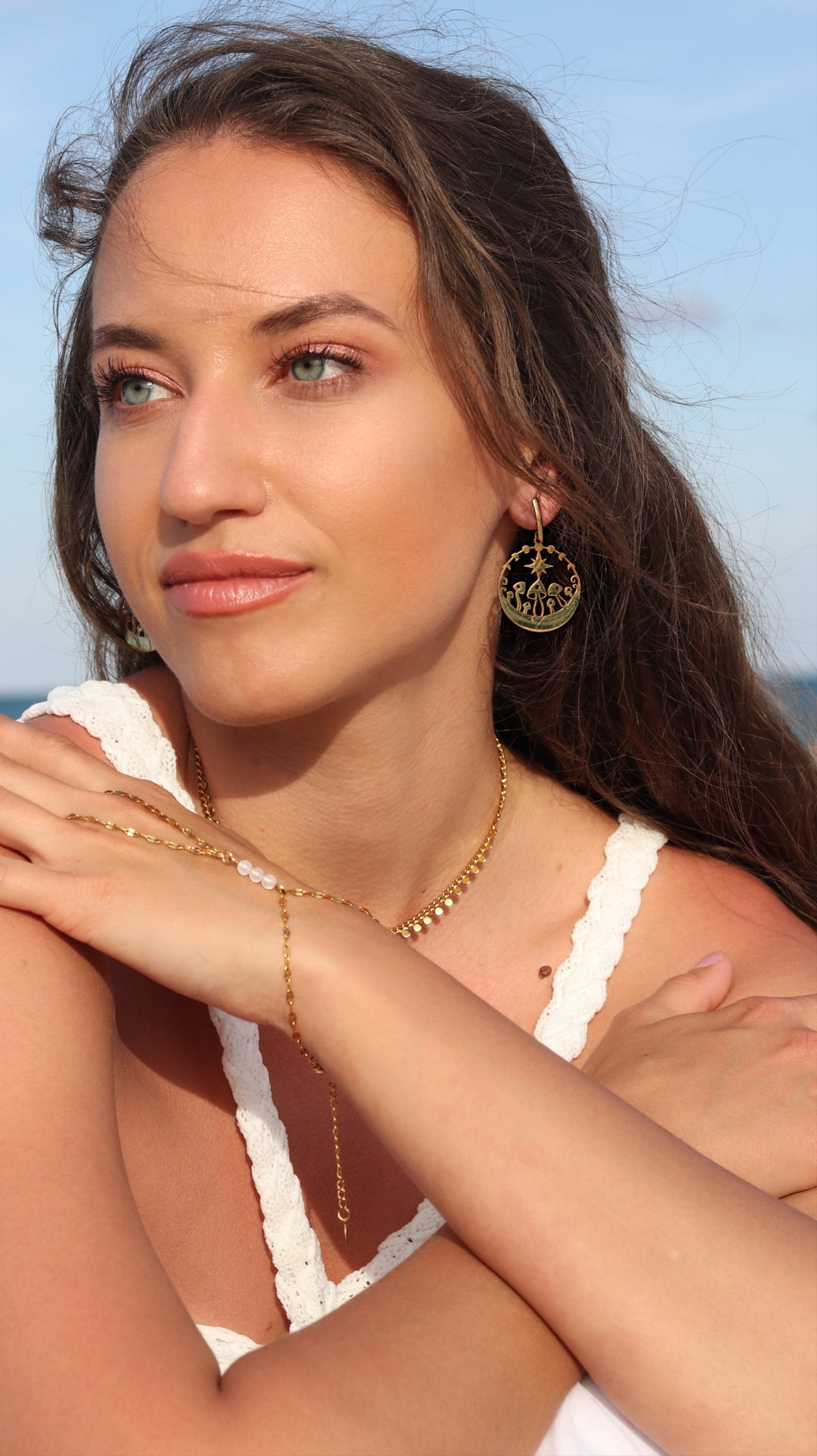 Close-up of woman's ear at the beach wearing a gold mushroom dangle earring — 18k gold plated stainless steel disc pendant by BURZAN Design
